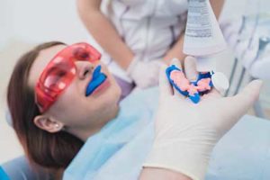 girl/woman lying back with red protective eyewear and a blue mouthguard, fluoride treatments tx