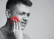 man holding cheek due to tooth pain, how to prevent tooth decay naturally