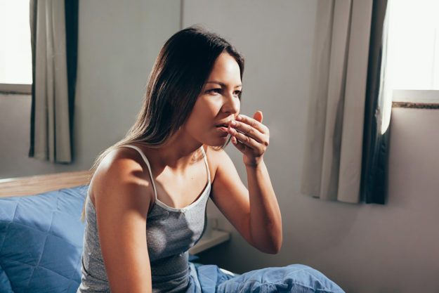 causes of bad breath (2) woman checking to see the causes of bad breath