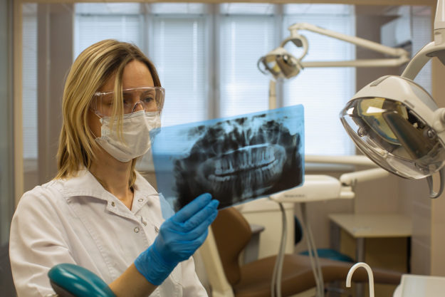 5 Signs You Need Dental Braces Again dentist looking at the need for dental braces for an adult patient
